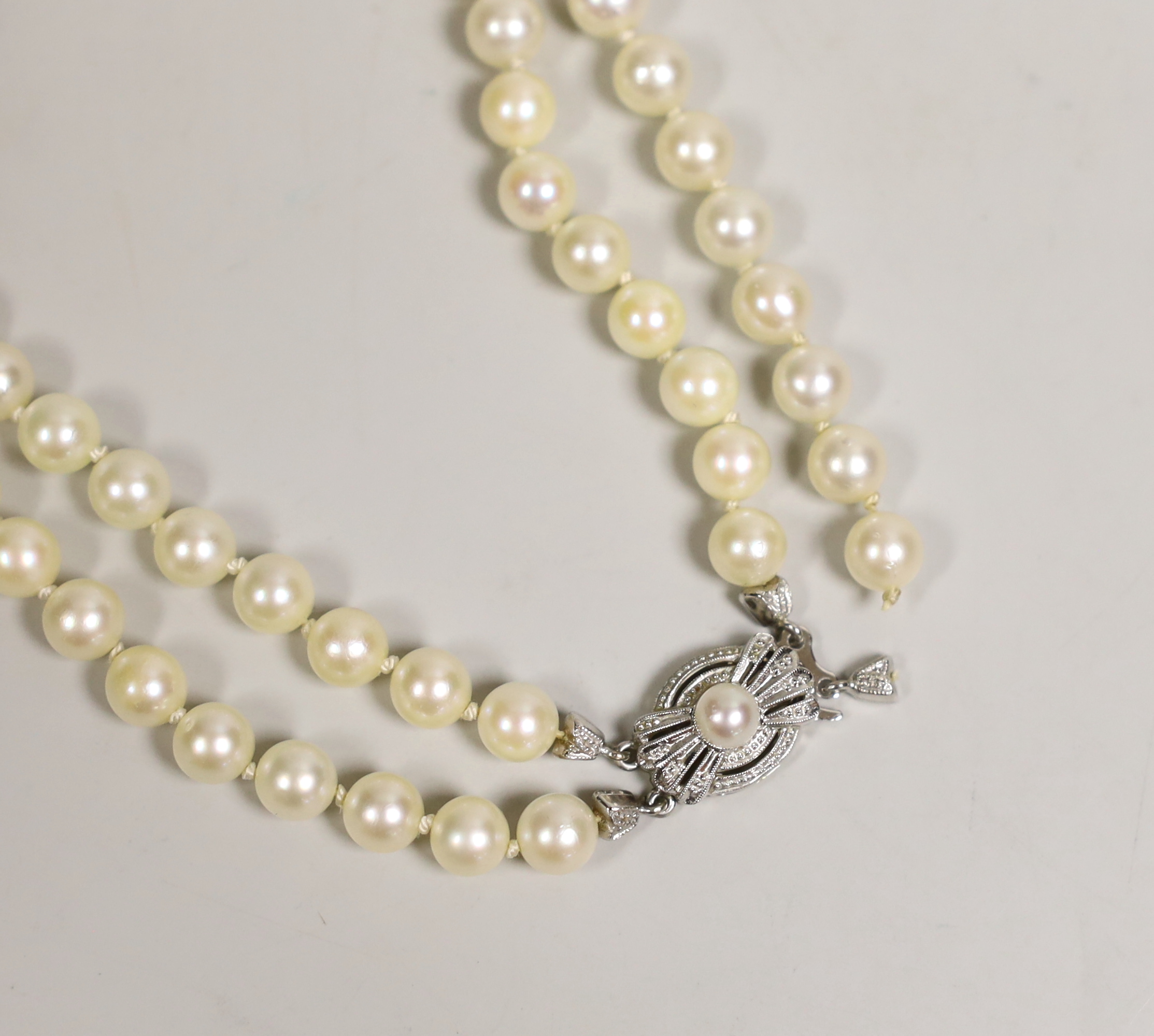 A mid to late 20th century double strand cultured pearl necklace, with cultured pearl set two colour 585 clasp, 43cm.